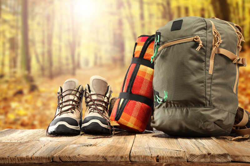 太阳森林背景下的旅行包与鞋子