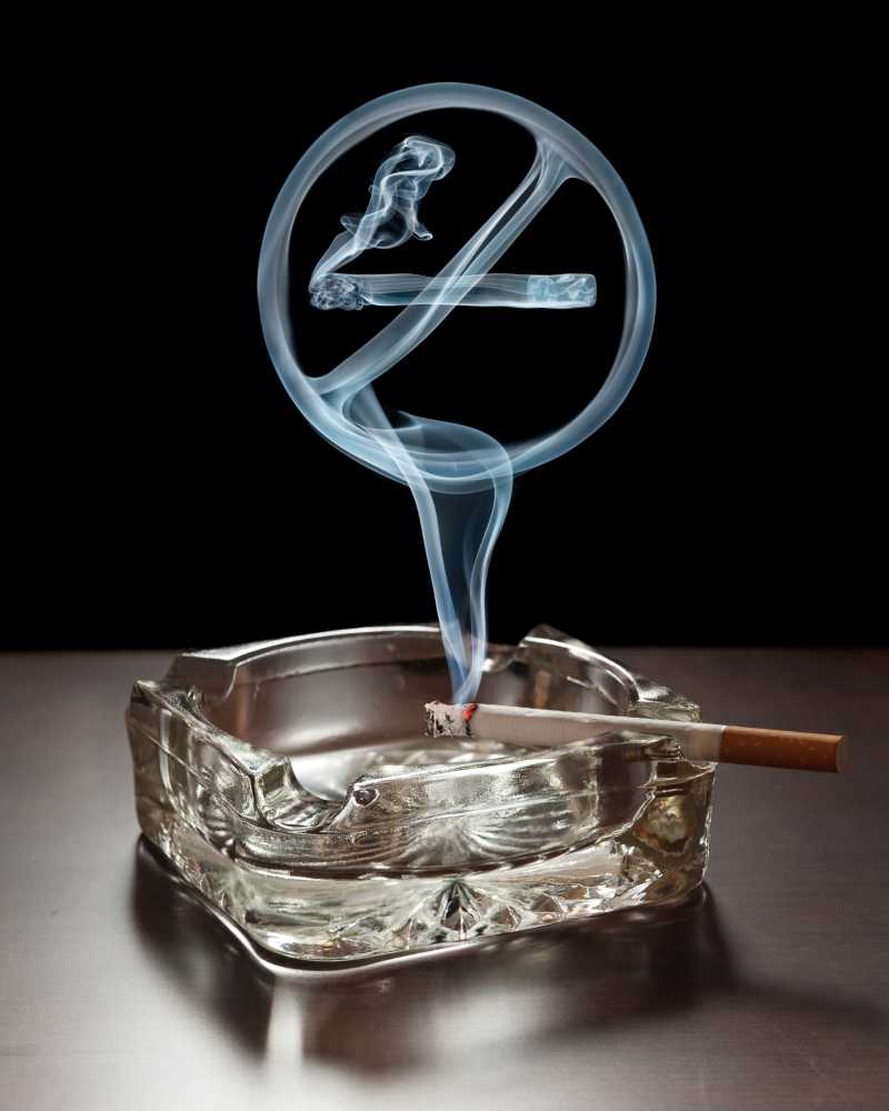 吸烟放在烟灰缸上方飘着禁止吸烟标志