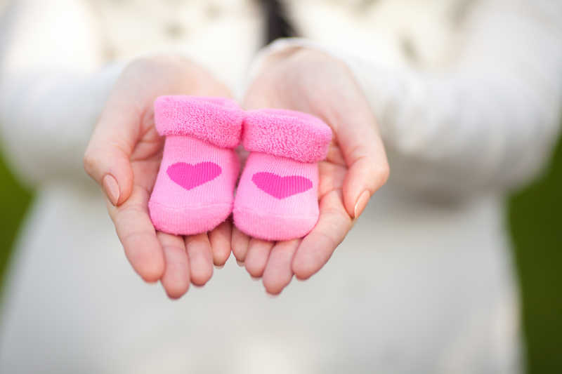 双手捧着粉红色婴儿鞋
