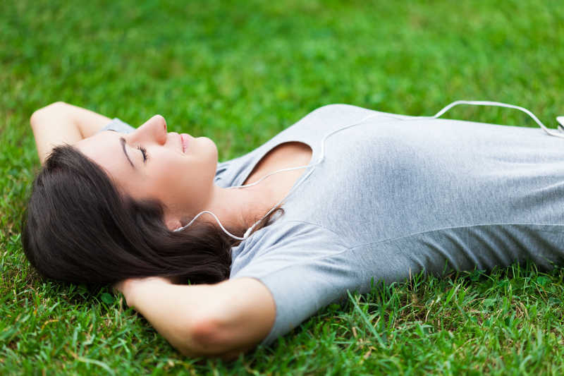 躺在草地上听音乐放松的女人