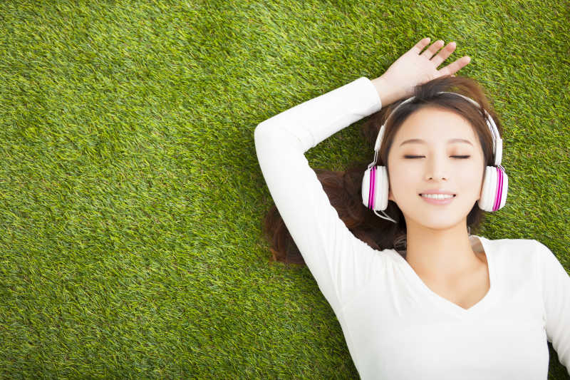 戴着耳机躺在草地上放松的女人