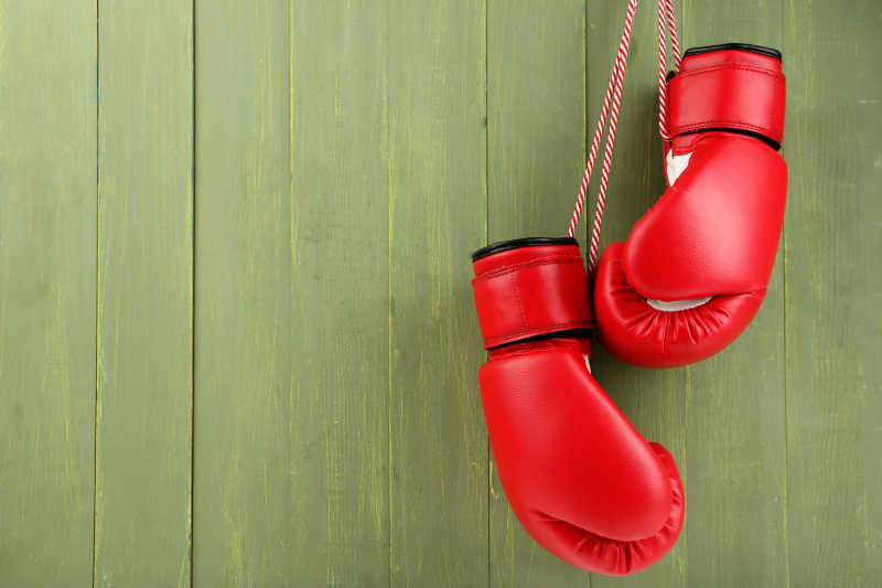 绿色木墙上的红色拳击手套