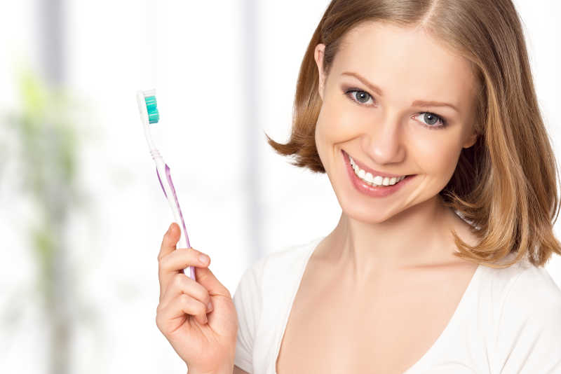 健康快乐的年轻女子雪白的微笑拿着牙刷
