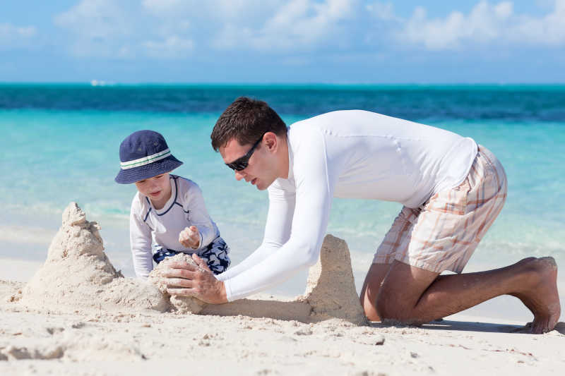 父亲和他的孩子在海边堆沙堡
