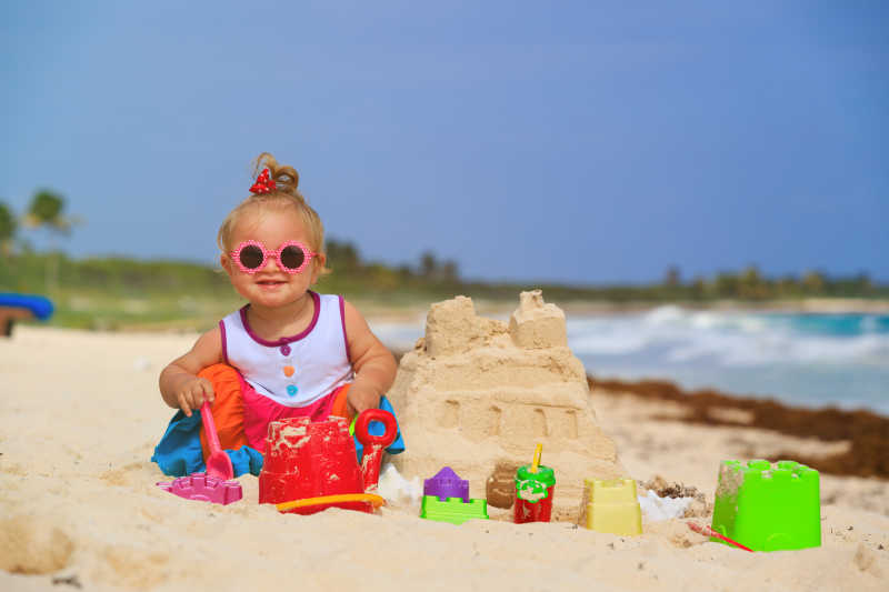 夏日海滩上玩沙子的小女孩