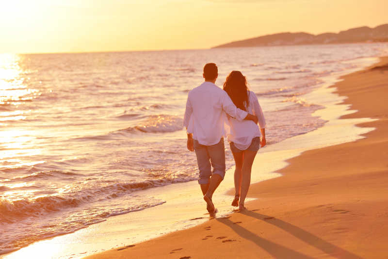 幸福的情侣在海边散步背影