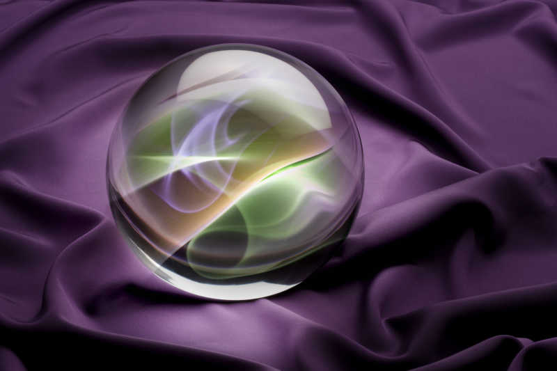 水晶球与彩色烟雾内部拍摄紫色缎子背景