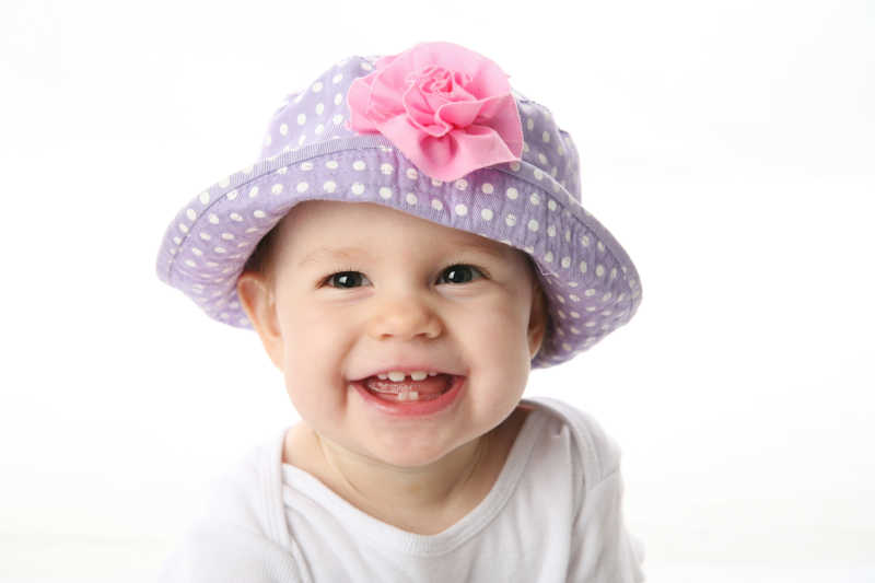 戴着紫色圆点帽子微笑的小女孩