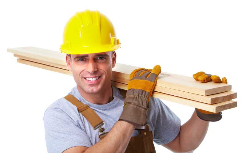 白色背景下戴着黄色安全帽戴着保护手套扛着木板的工人