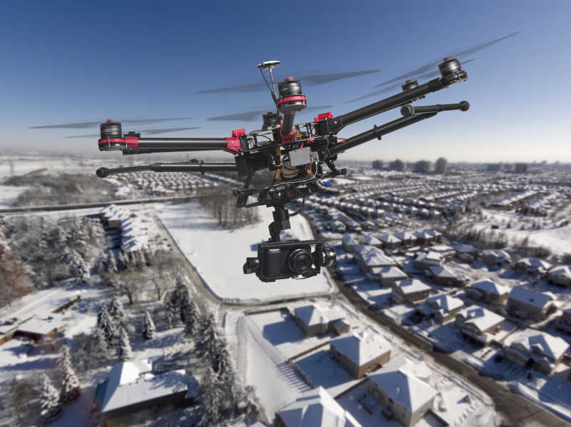 在晴朗的冬日一架无人机带着照相机和起落架在居民区上空飞行