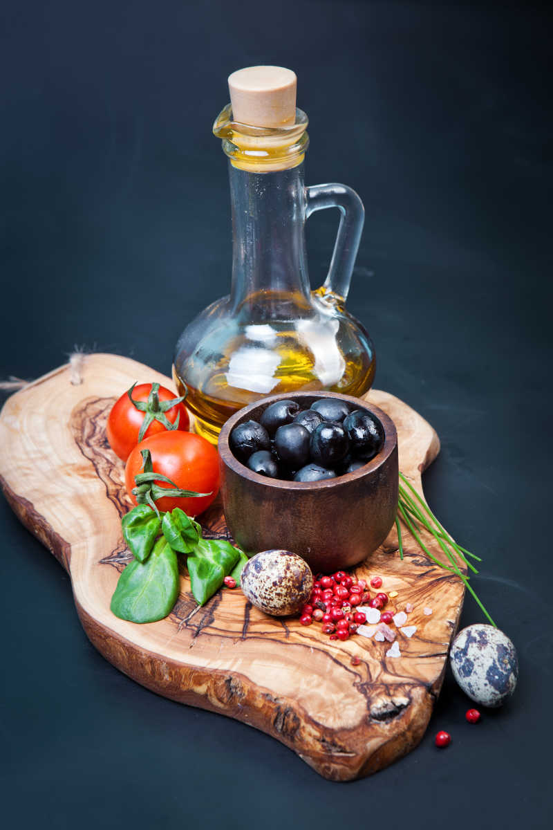木桌上的黑橄榄番茄配料和一瓶油