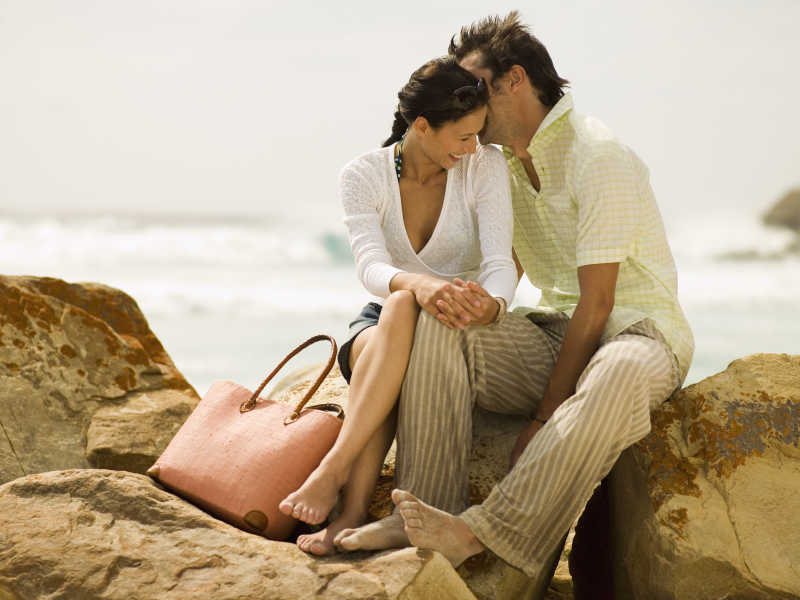 海滩上的岩石上浪漫度假的夫妇