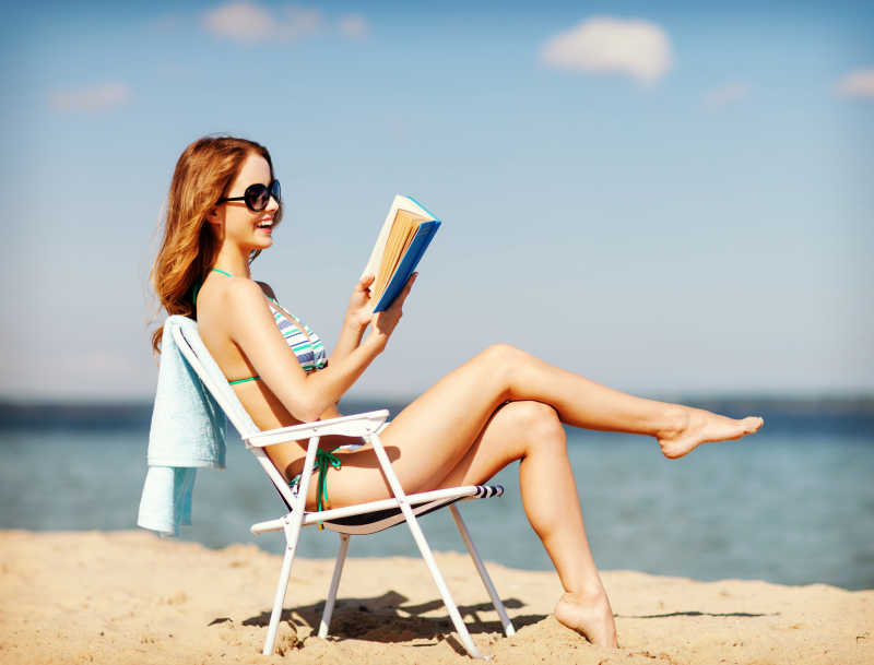 沙滩椅上身穿性感比基尼读书的女孩