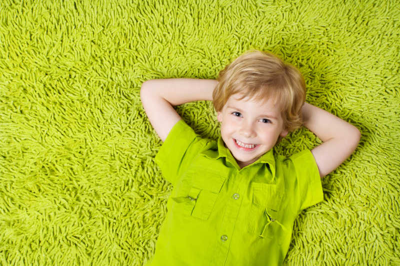 躺在绿色地毯上的快乐孩子