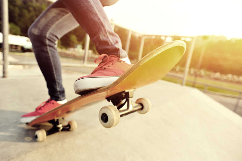 夕阳下玩滑板的年轻人腿部特写