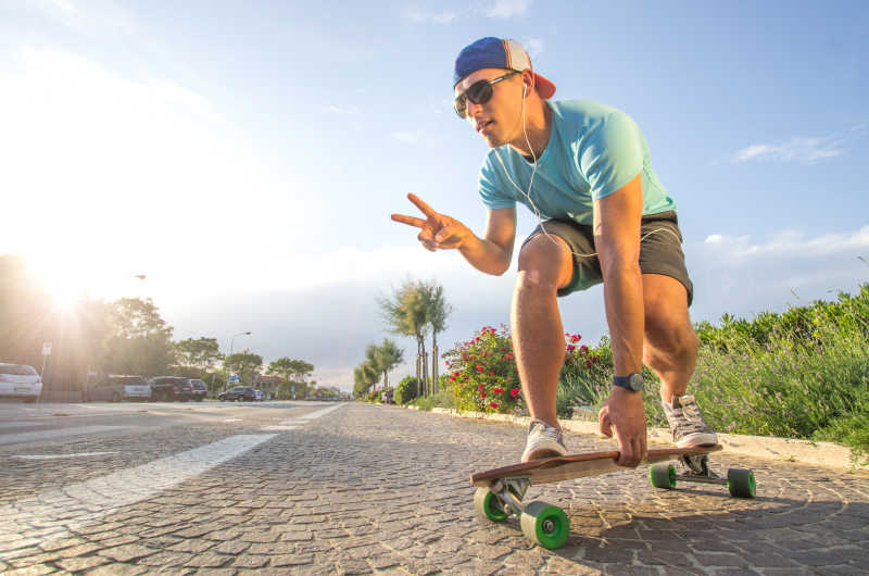 在城市道路上玩滑板自拍的年轻男子