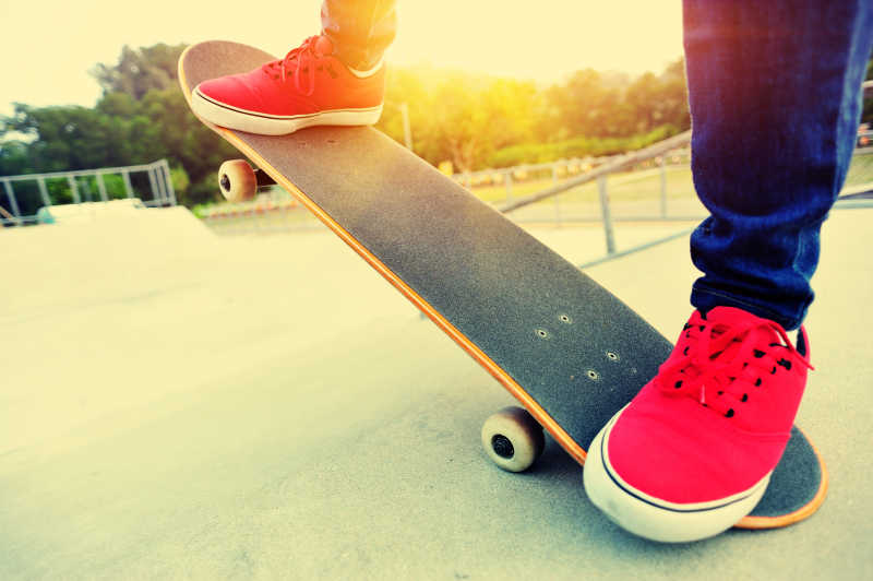 夕阳下玩滑板的年轻女子脚部特写