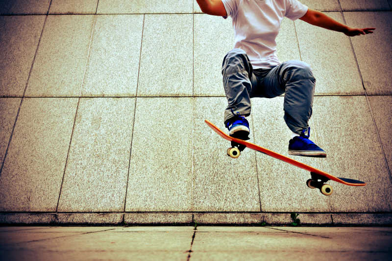 城市街头玩滑板跳跃的年轻男孩