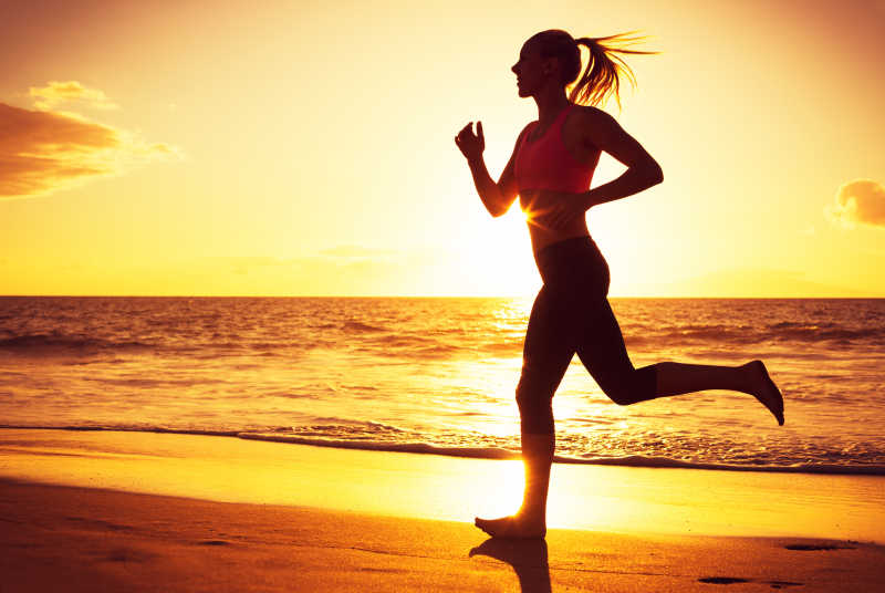 日落时分在海滩上奔跑的女人