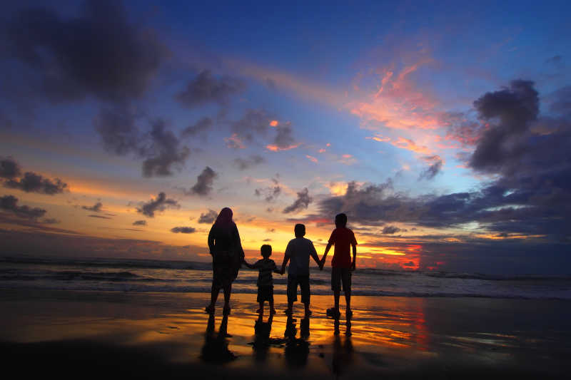在海滩上看日落景观的一家人