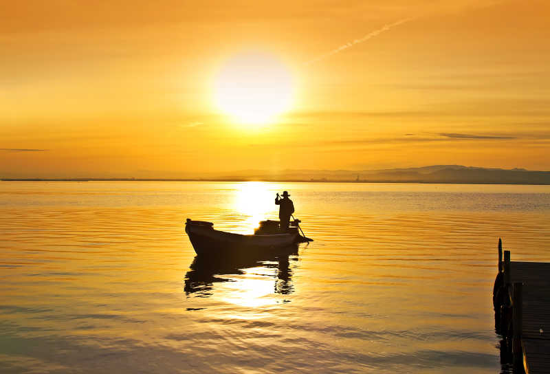 落日时分在海上渔船上行驶的人