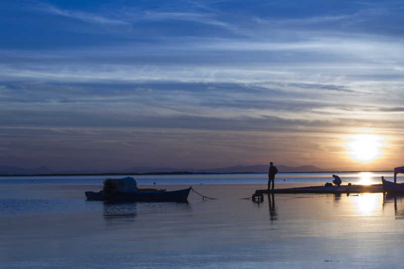 日落时分海边归来的渔船和渔民
