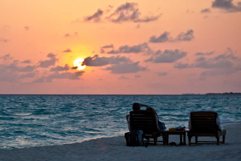 在海边的躺椅上欣赏落日景观的人