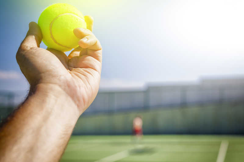 阳光下网球运动员拿着网球准备发球