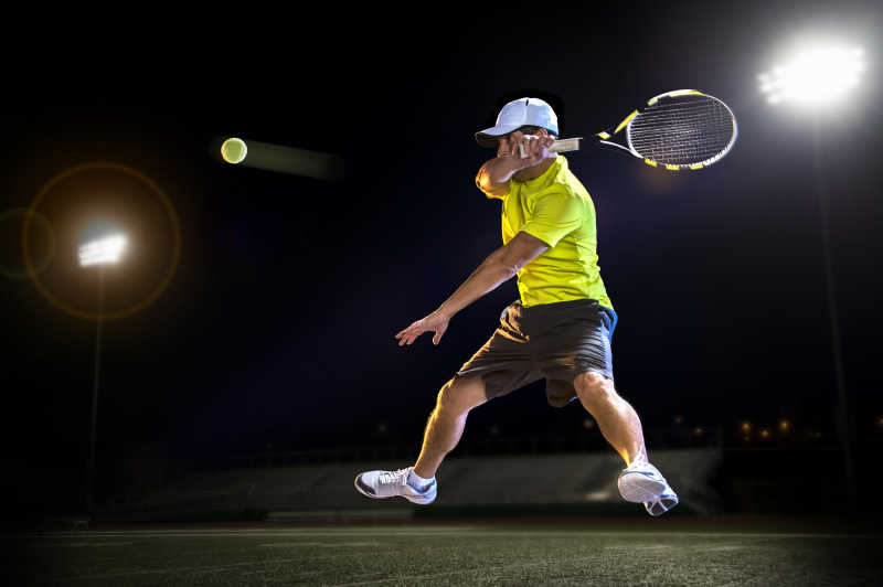 灯光下打网球的运动员
