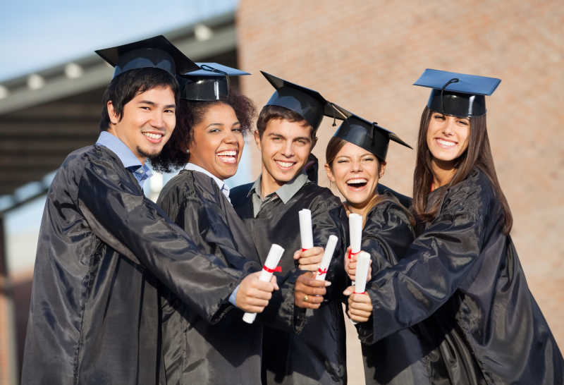 毕业典礼上穿着黑色礼服带着博士帽展示文凭的大学生