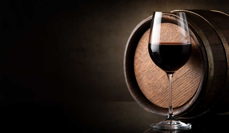 红葡萄酒和桶在棕色背景的酒杯