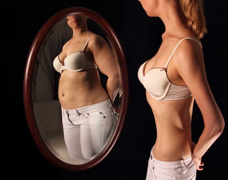 骨瘦如柴的女人在镜中看到自己肥胖
