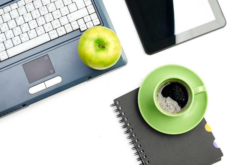 放在笔记本电脑上的青苹果和放在笔记本上的咖啡