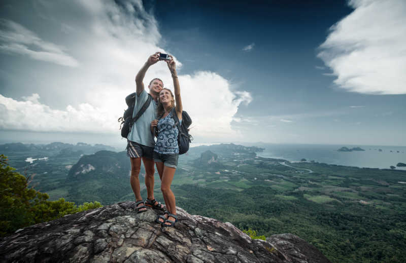 年轻的情侣旅行者在山顶上拍照