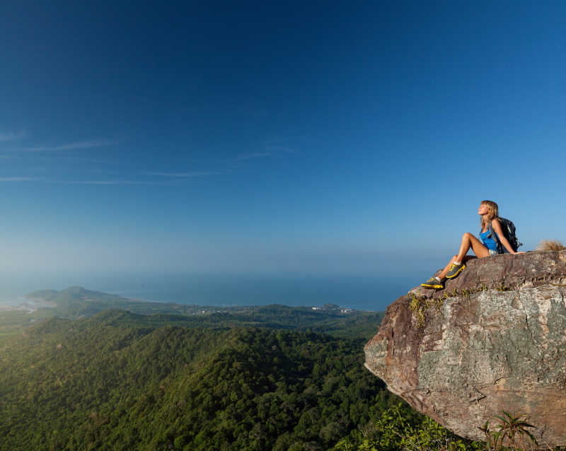 坐在山顶的岩石上的年轻女子