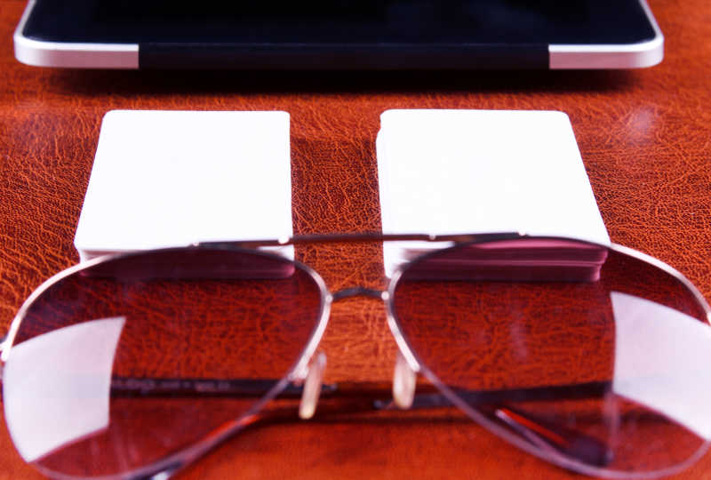红色桌面上的笔记本白色卡片和太阳眼镜