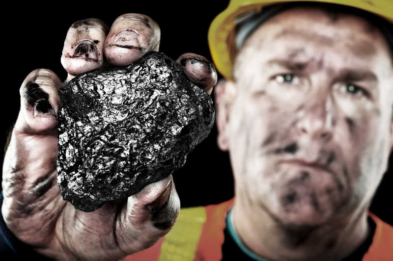脸上都是煤印的矿工手拿大块煤炭