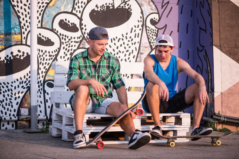 两个玩滑板的年轻男人坐在白椅上
