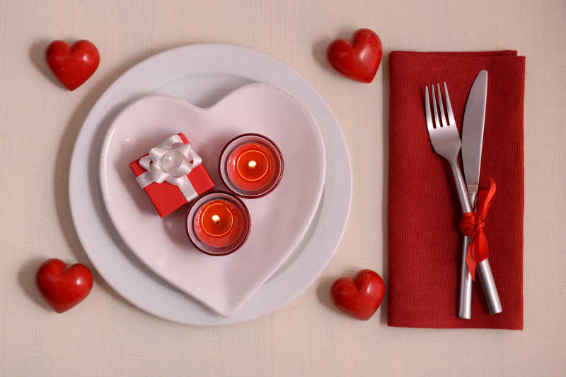 摆放整齐的浪漫餐具和红色爱心还有礼物