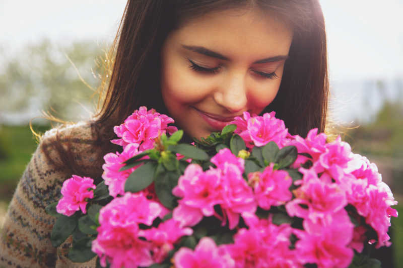 女人闻到粉红色的花微笑