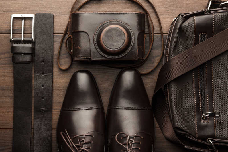 木桌上的棕色鞋腰带包和胶卷相机