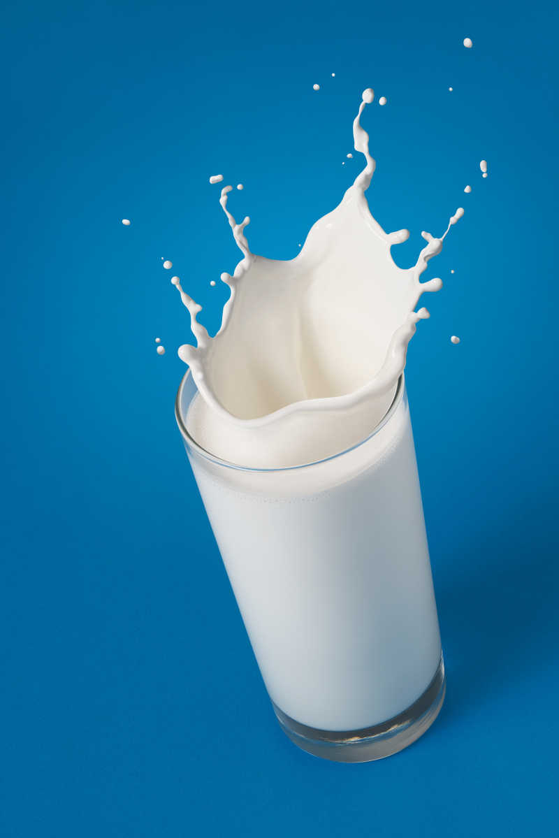 一杯溅在蓝色背景上的牛奶