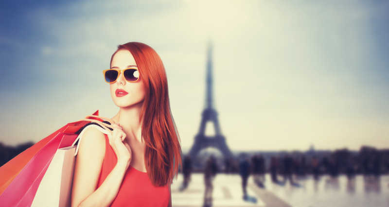 巴黎铁塔背景下提着购物袋的女人