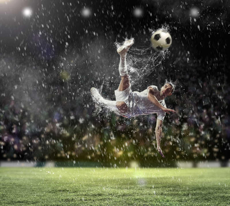下雨时在足球场飞身踢足球的足球运动员
