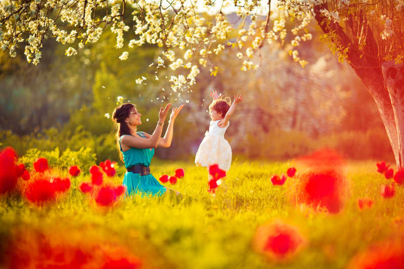 幸福的女人和孩子在盛开的春天花园