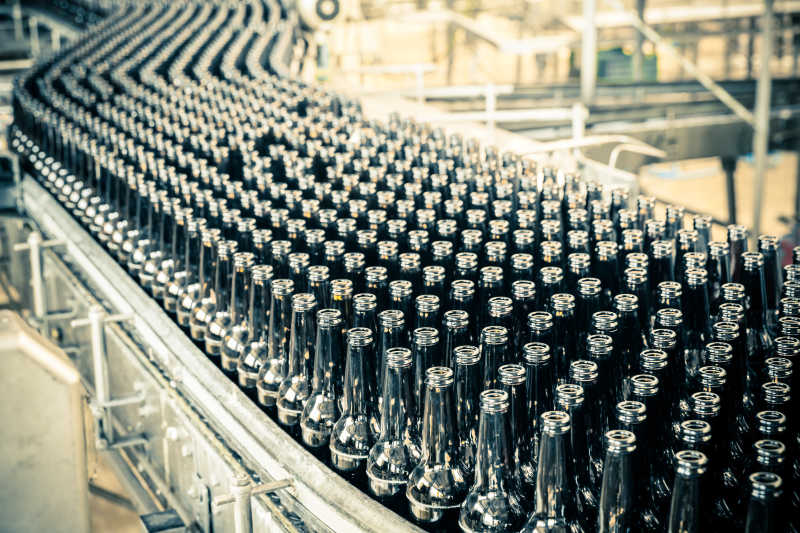 现代化啤酒厂传送带上整齐的黑色的啤酒瓶