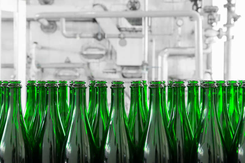 工厂里传送带上排放整齐的绿色的瓶子