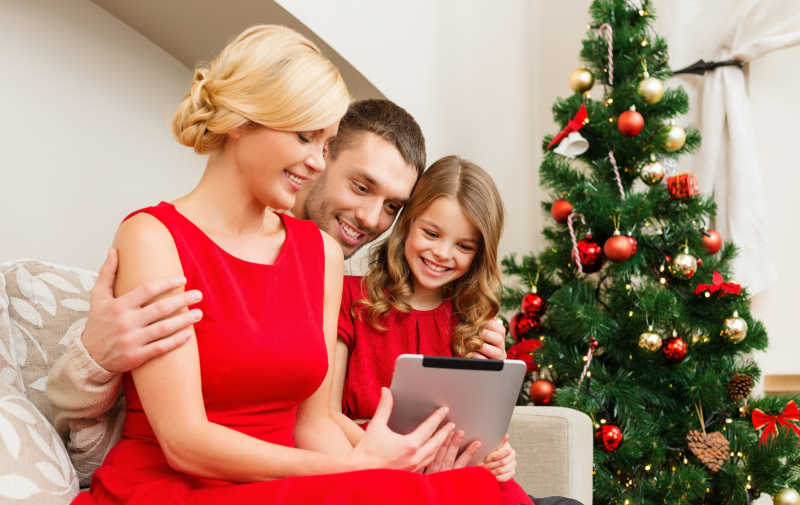 微笑家庭在圣诞节看平板电脑