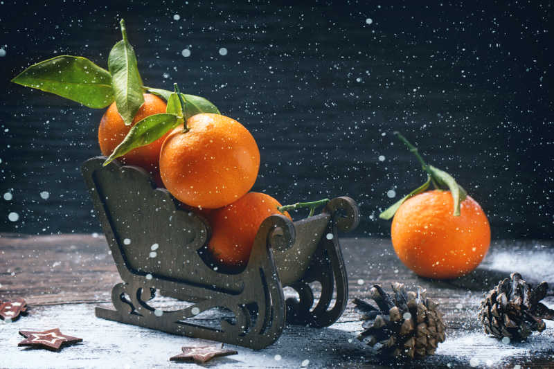 雪天木色桌面上的木制雪橇上的橘子