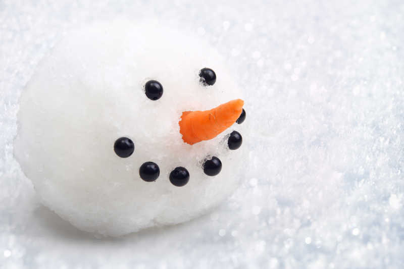 白色雪地上的有胡萝卜鼻子的雪人头部